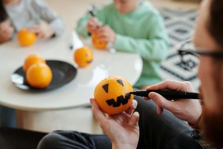 Family enjoys creative Halloween activity by painting oranges indoors, bonding and having fun together.