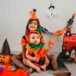 two children dressed up as witches sitting on the floor