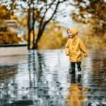 child in brown coat standing on water during daytime