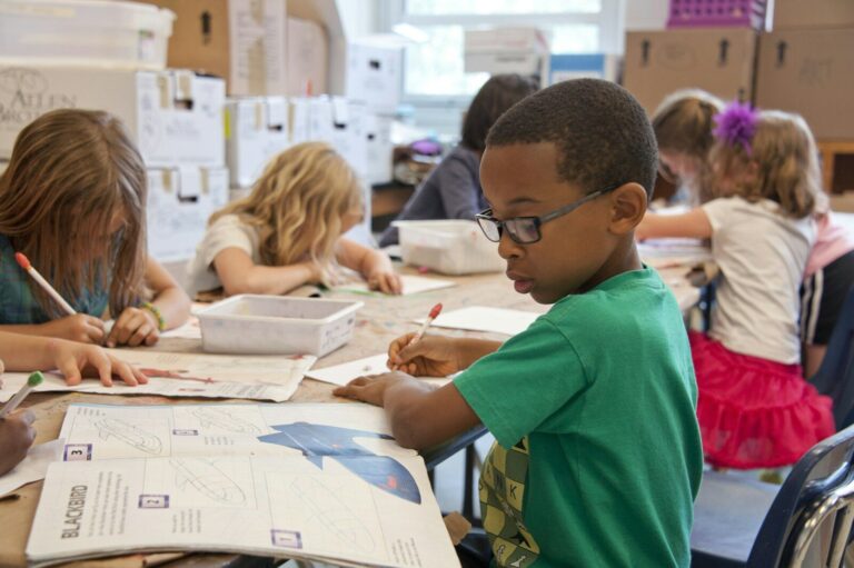 Back to School Supplies - The Official Guide for Parents boy in green sweater writing on white paper